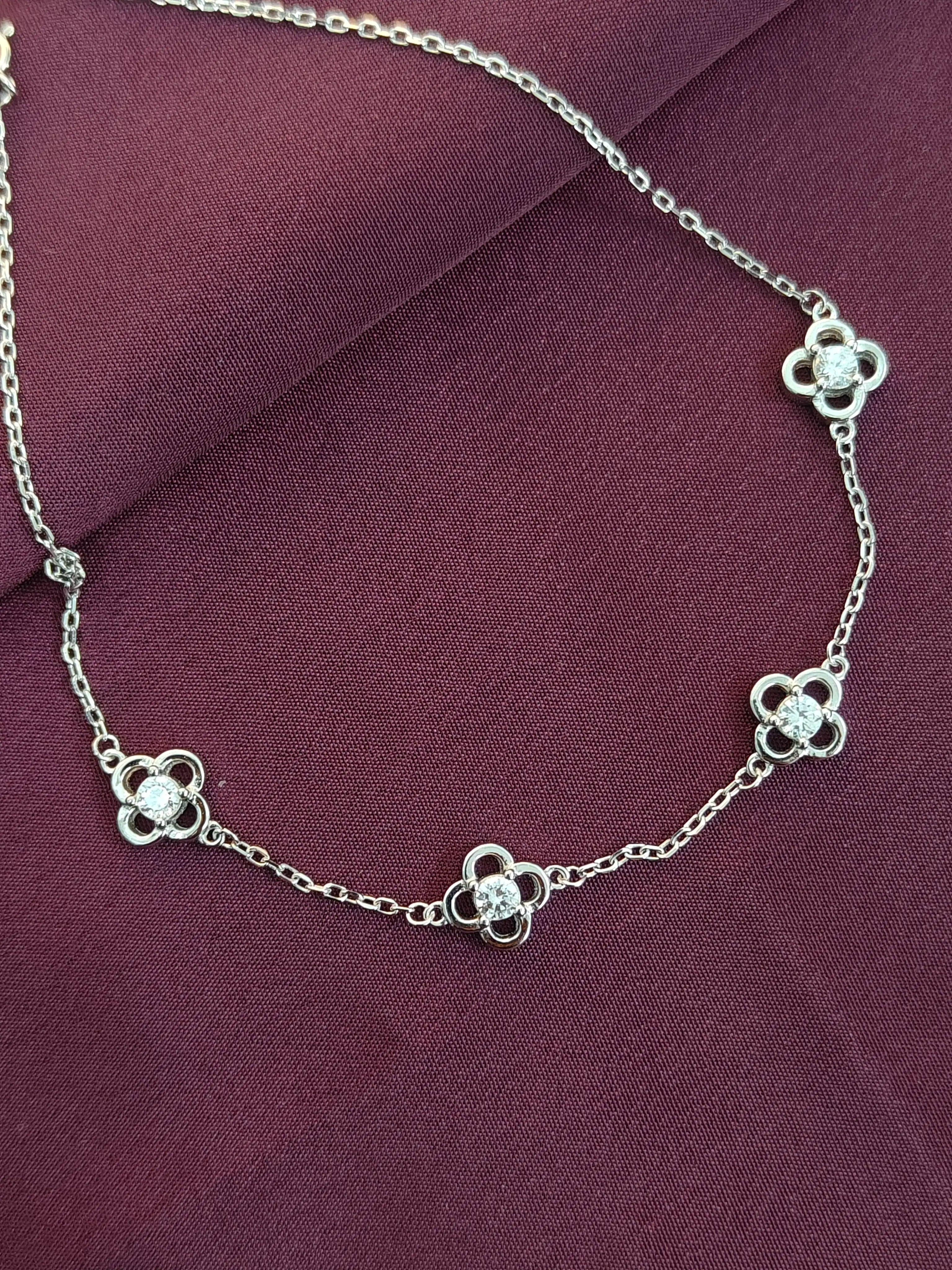 Silver necklace with floral designs on a purple fabric background